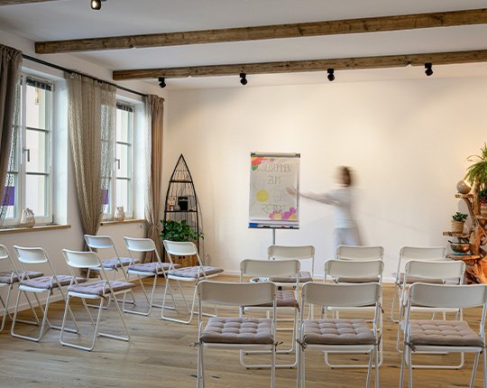 Heller Seminarraum mit Stuhlreihen, Johanna bereitet ein Coaching vor.
