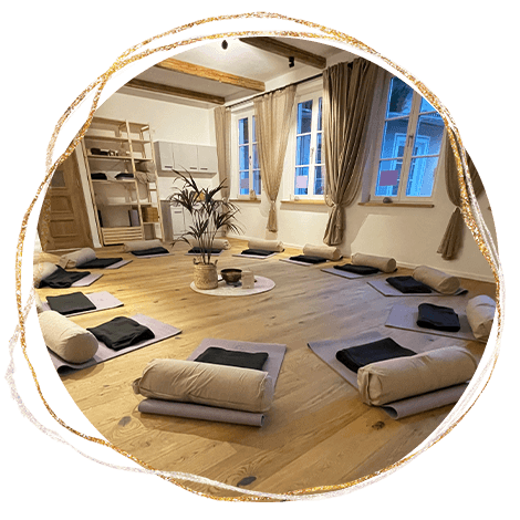Heller Raum mit im Kreis angeordneten Yogamatten und Sitzkissen für Gruppenarbeit.