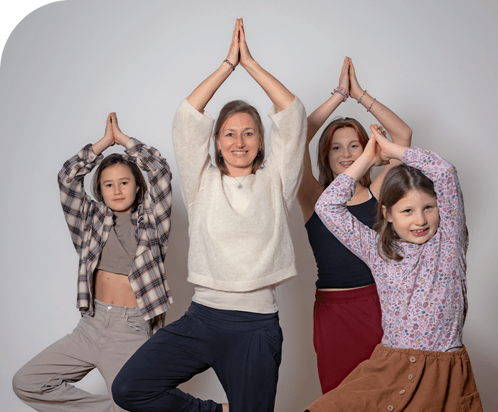 Johanna mit drei Mädchen machen gemeinsam eine Yoga-Pose mit erhobenen Händen – ruhige, familiäre Atmosphäre passend zu Achtsamkeit und innerer Balance.