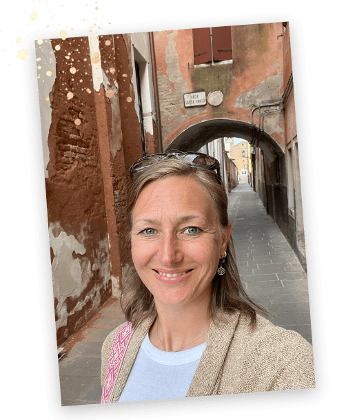 Johanna lächelt in einer schmalen Gasse mit historischem Torbogen.