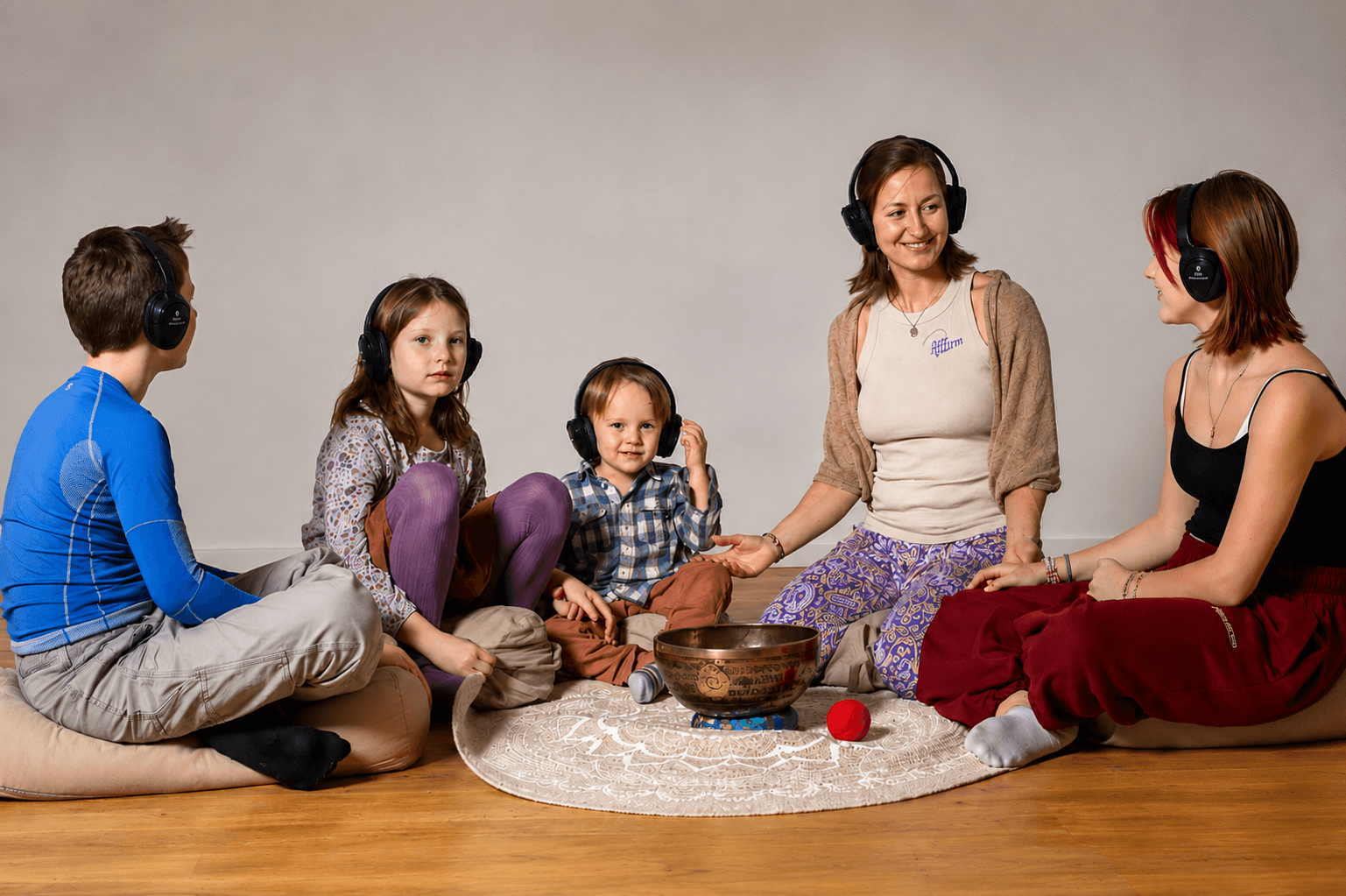 Johanna Stuefer sitzt mit Kindern im Kreis mit Kopfhörern und Klangschale bei einer Neurotunes-Meditation